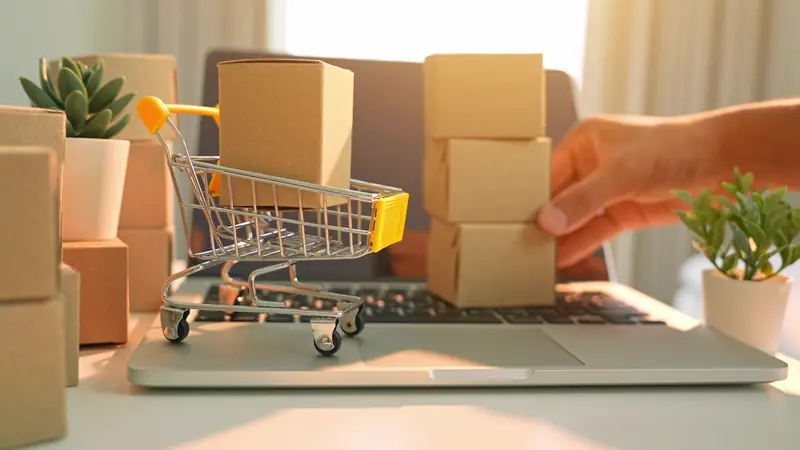 Kleiner Einkaufswagen mit Paketen steht auf einer Laptop-Tastatur